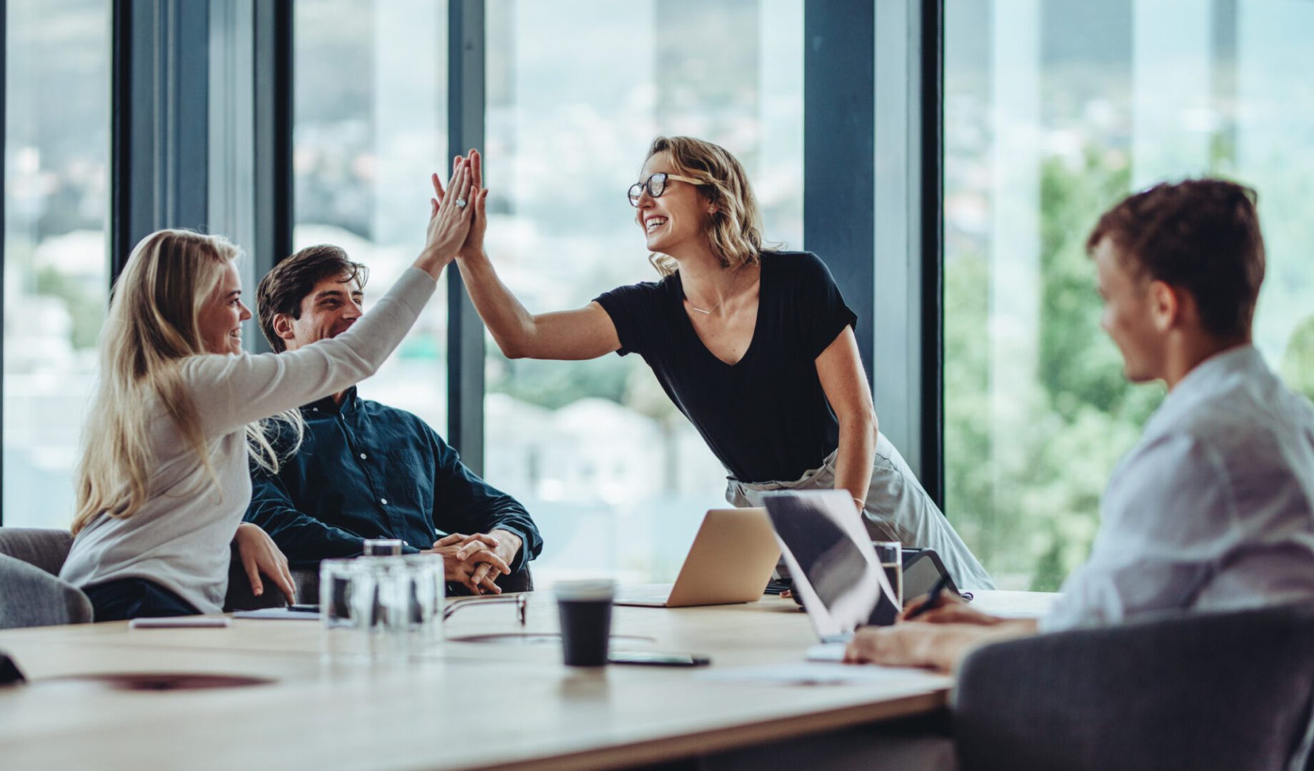 Team celebrating with a high-five in office.