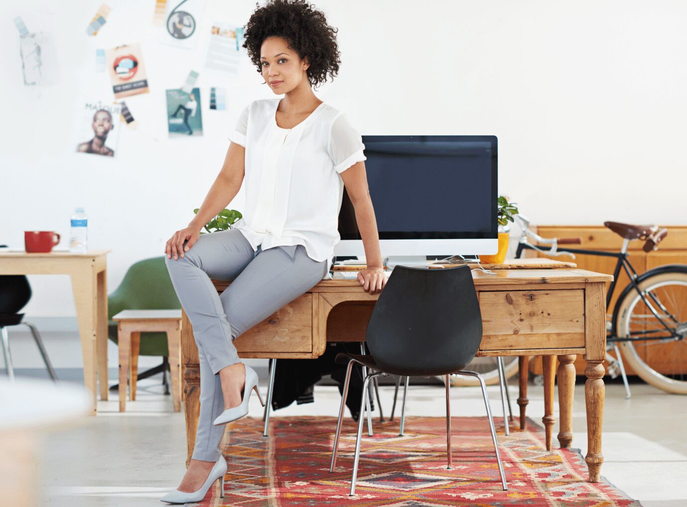 Person sitting on desk in modern office.