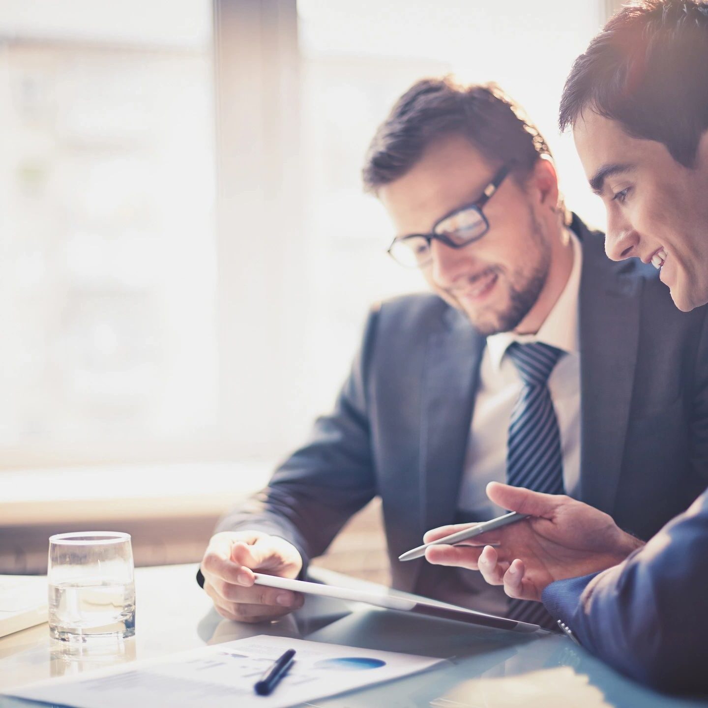 Two businessmen reviewing documents together in a bright office.