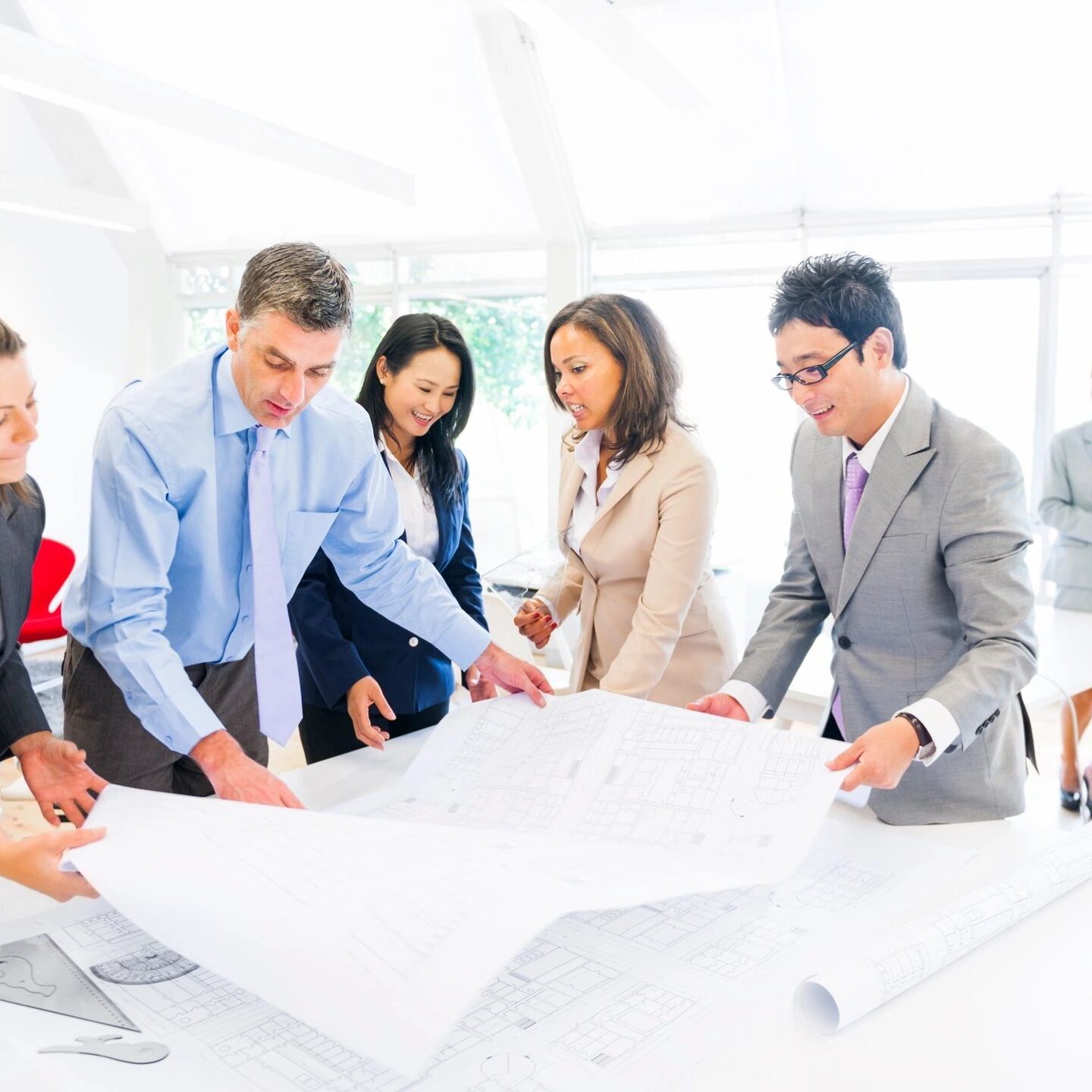 A group of professionals collaborating around a large blueprint.