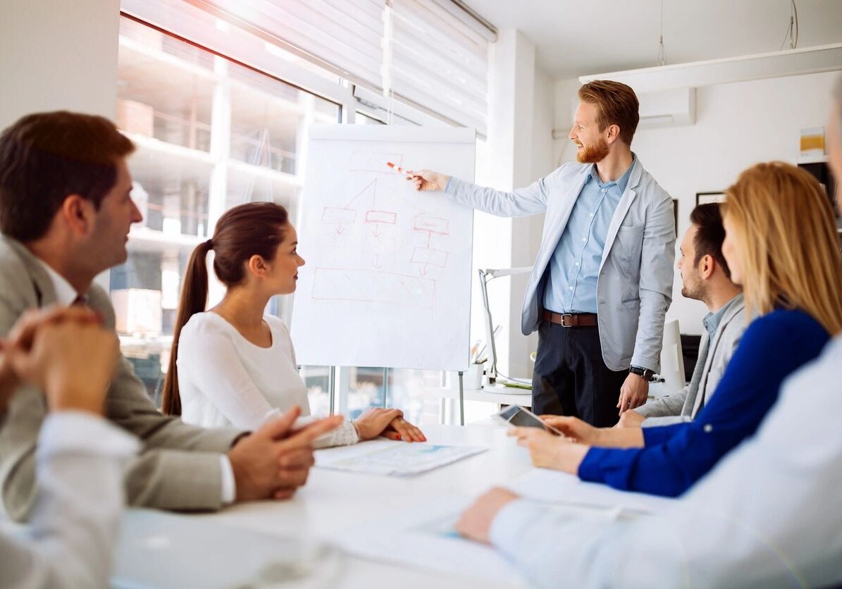 Business meeting with a man presenting to colleagues in a bright office.